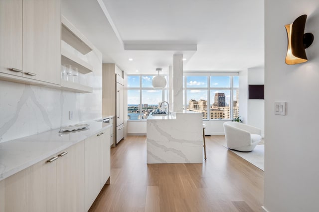 kitchen featuring light stone countertops, light wood finished floors, modern cabinets, and decorative backsplash