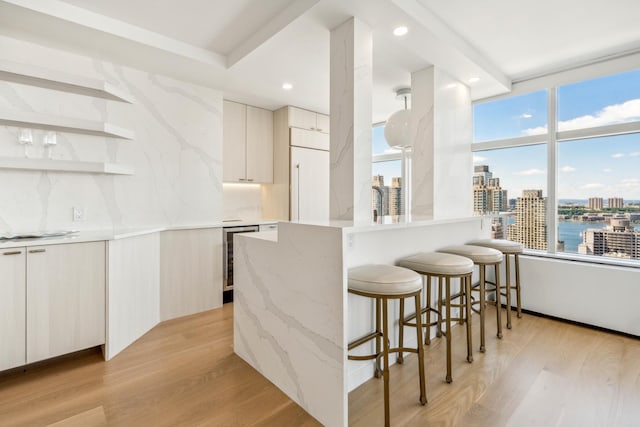 kitchen with a kitchen bar, a view of city, modern cabinets, and light wood finished floors