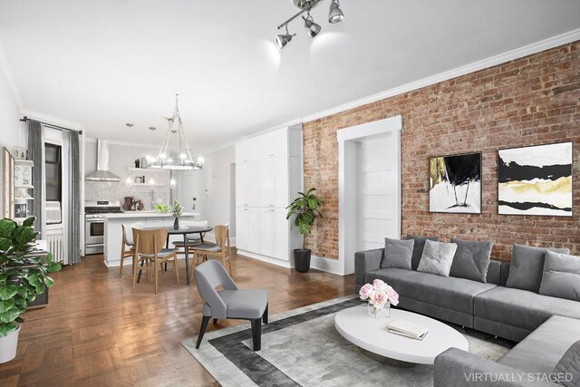 living room featuring a notable chandelier, crown molding, parquet floors, and brick wall