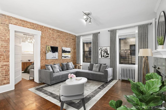 living room with crown molding, brick wall, radiator heating unit, and dark parquet floors