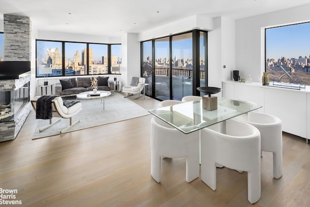 dining space featuring a view of city, a stone fireplace, and light wood-style flooring