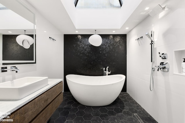 full bath featuring tile patterned floors, a freestanding tub, vanity, and recessed lighting