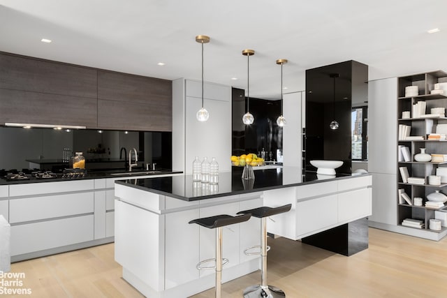 kitchen featuring dark countertops, modern cabinets, a sink, and a center island