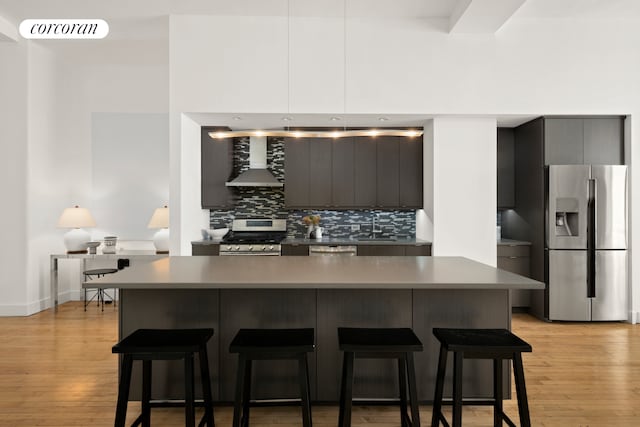 kitchen with visible vents, appliances with stainless steel finishes, a sink, wall chimney range hood, and modern cabinets