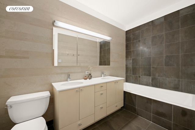 bathroom featuring tile walls, a relaxing tiled tub, toilet, and a sink