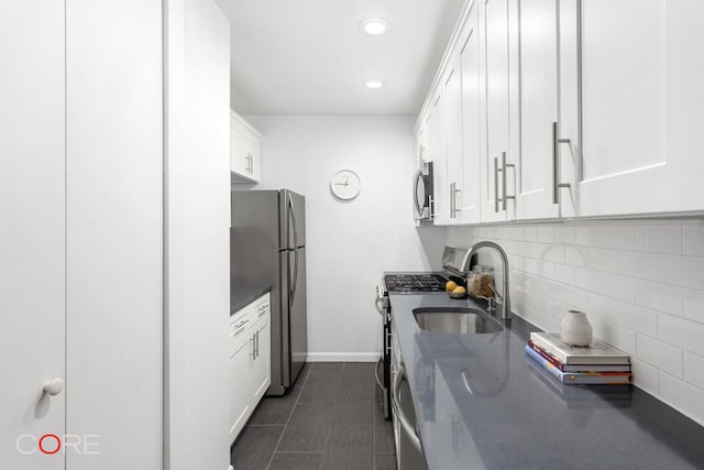 kitchen featuring appliances with stainless steel finishes, dark tile patterned floors, white cabinetry, decorative backsplash, and sink