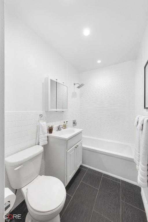 full bathroom with tiled shower / bath combo, tile patterned flooring, vanity, tile walls, and toilet