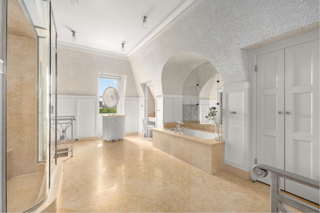bathroom with crown molding, a walk in shower, wainscoting, a decorative wall, and a bath