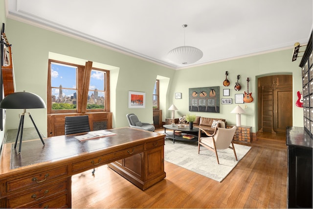 office featuring crown molding, arched walkways, and light wood-style floors