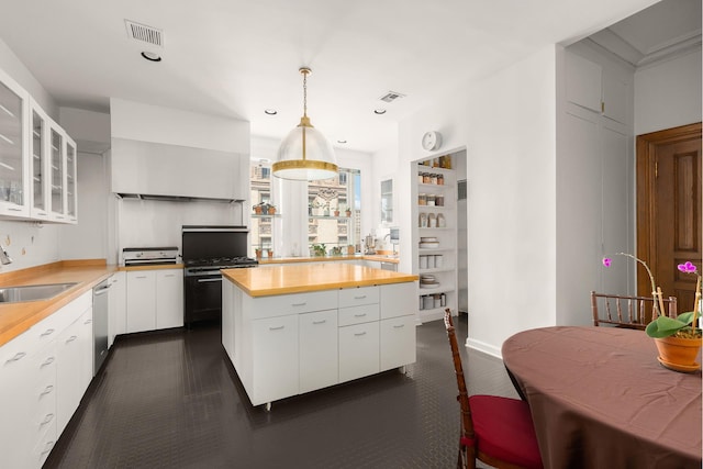1 W 72nd St Unit 84, New York City, NY 10023 - kitchen featuring wood counters, stainless steel dishwasher, a sink, white cabinetry, and glass insert cabinets
