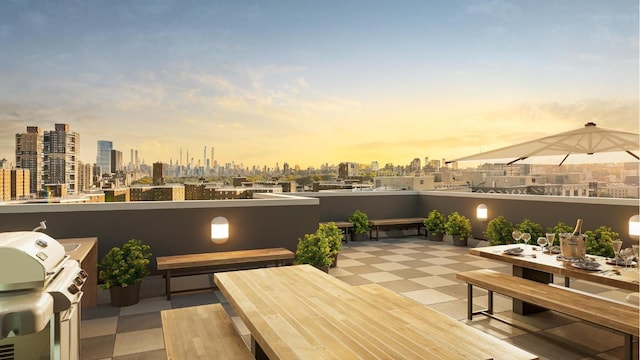 patio terrace at dusk featuring area for grilling and a balcony