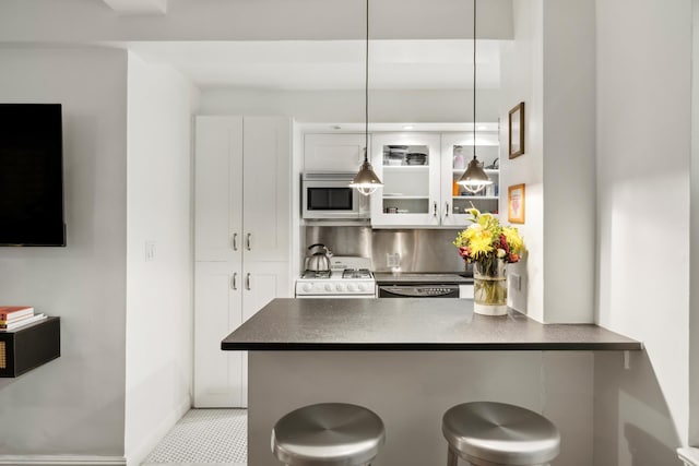 kitchen featuring dark countertops, white gas range, white cabinetry, and a peninsula