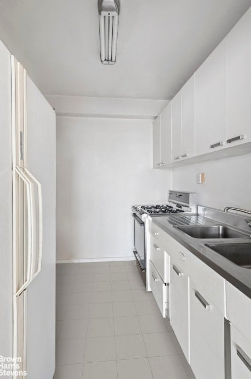 kitchen with white cabinets, stainless steel range with gas stovetop, and white fridge