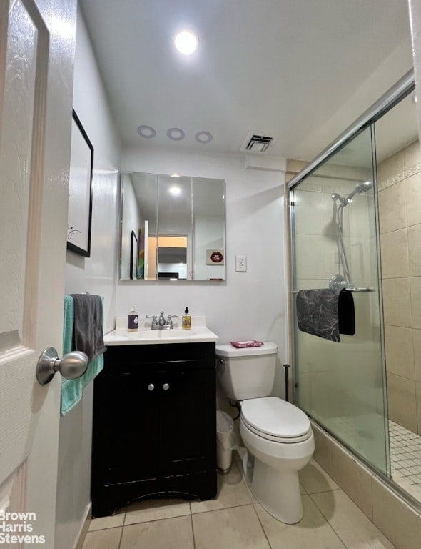 bathroom featuring walk in shower, vanity, toilet, and tile patterned flooring