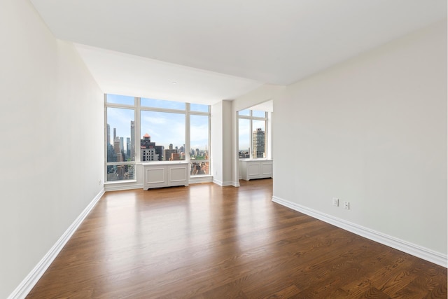 spare room with baseboards, dark wood finished floors, and a city view