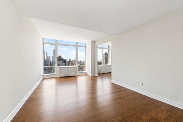 401 E 60th St Unit 38Ab, New York City, NY 10065 - spare room with baseboards, dark wood finished floors, and a city view