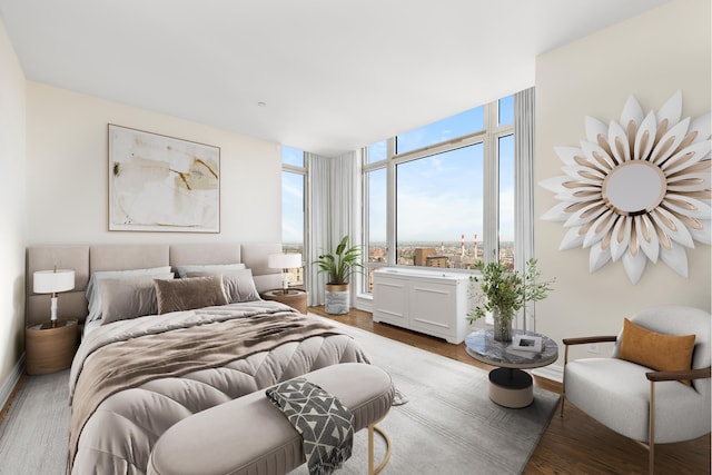 bedroom with baseboards, floor to ceiling windows, and wood finished floors