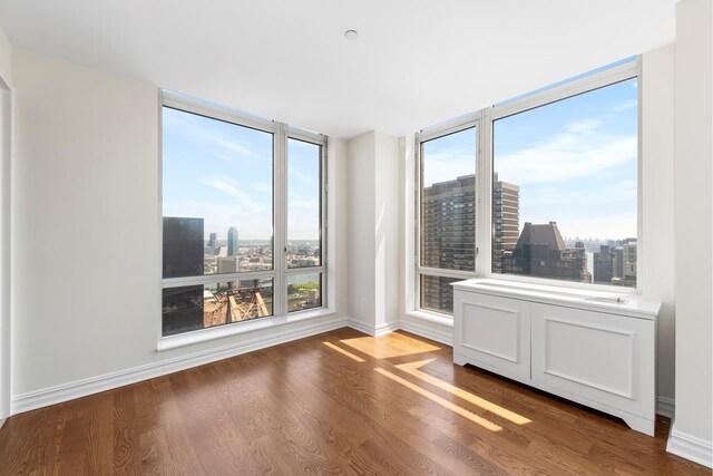 401 E 60th St Unit 38Ab, New York City, NY 10065 - unfurnished room featuring baseboards, a city view, and wood finished floors