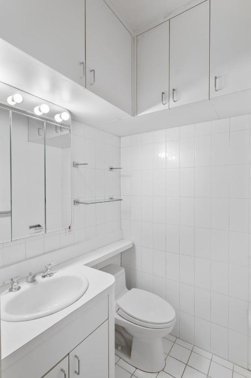 bathroom featuring tile walls, toilet, vanity, and tile patterned flooring