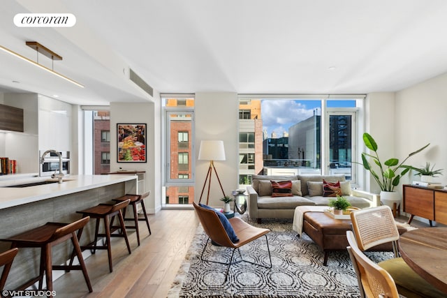 living area featuring expansive windows, visible vents, light wood-style flooring, and a view of city