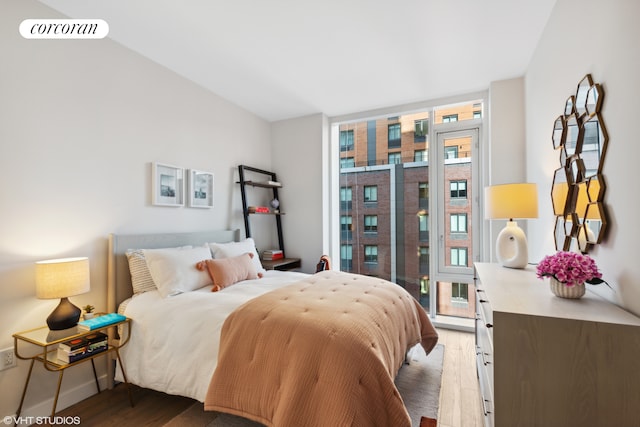 bedroom featuring baseboards, floor to ceiling windows, visible vents, and wood finished floors