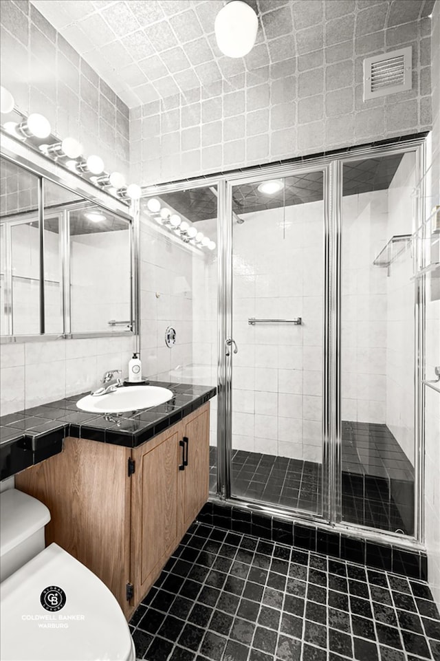 bathroom featuring tasteful backsplash, a shower stall, tile walls, and vanity