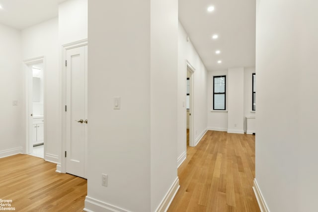 hallway with baseboards, light wood-style flooring, and recessed lighting