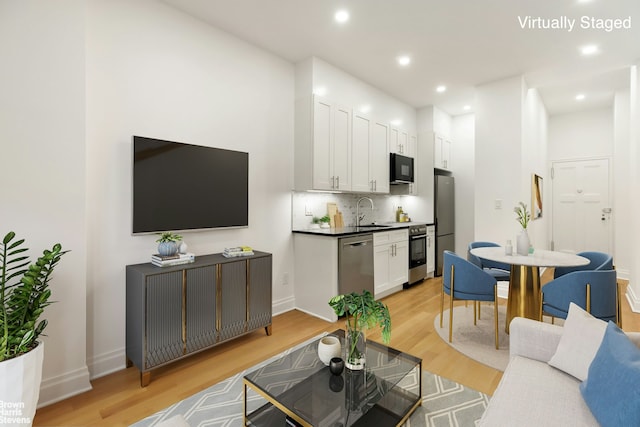 living area featuring baseboards, recessed lighting, and light wood-style floors