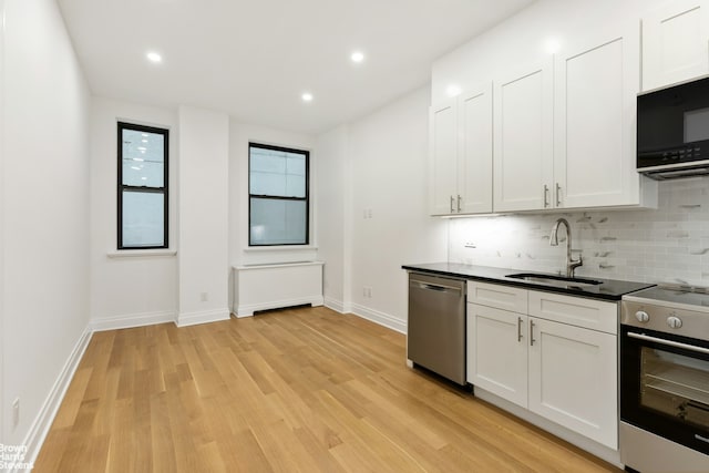 kitchen featuring a sink, white cabinetry, appliances with stainless steel finishes, tasteful backsplash, and dark countertops