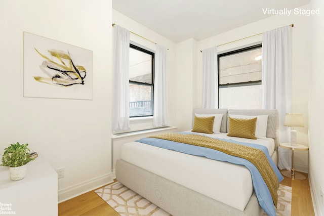 bedroom featuring light wood finished floors and baseboards