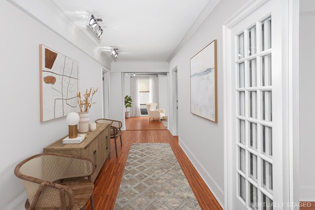 hall with ornamental molding, light wood-type flooring, and baseboards