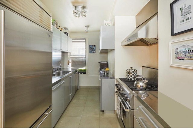 kitchen featuring sink, white cabinets, premium appliances, stainless steel counters, and light tile patterned floors