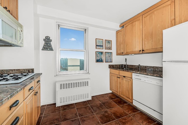 kitchen featuring sink, radiator, dark stone countertops, and white appliances