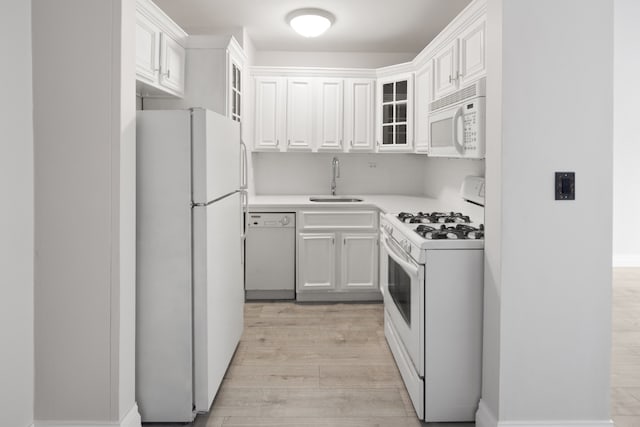 kitchen with sink, white appliances, white cabinetry, and light hardwood / wood-style flooring