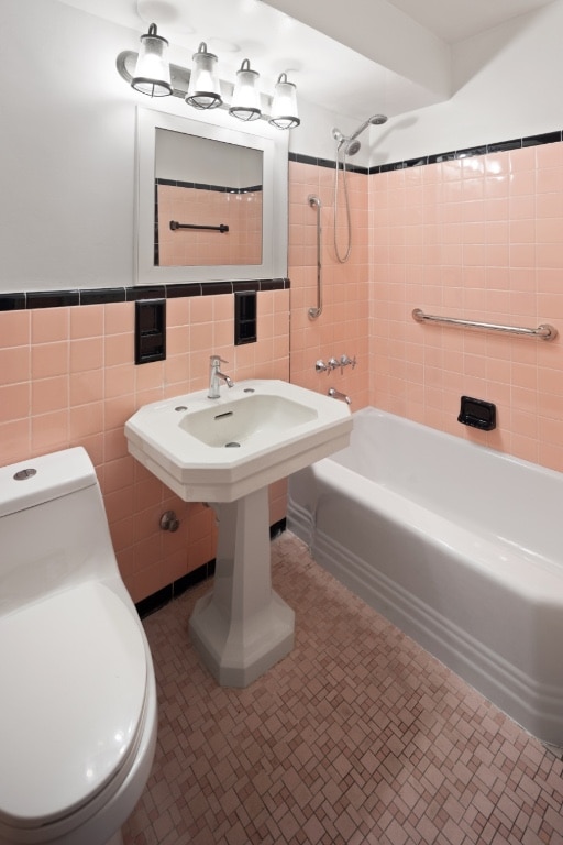 bathroom featuring toilet, tile walls, tile patterned floors, and tiled shower / bath combo