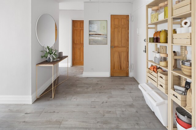 corridor with light wood-style flooring and baseboards