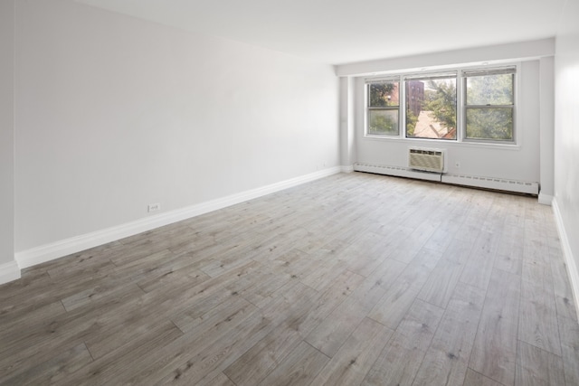 unfurnished room featuring baseboard heating and light hardwood / wood-style floors