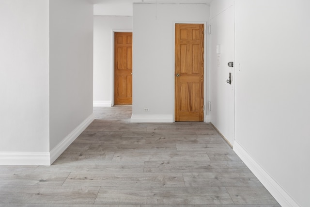 unfurnished room featuring baseboard heating and light hardwood / wood-style floors