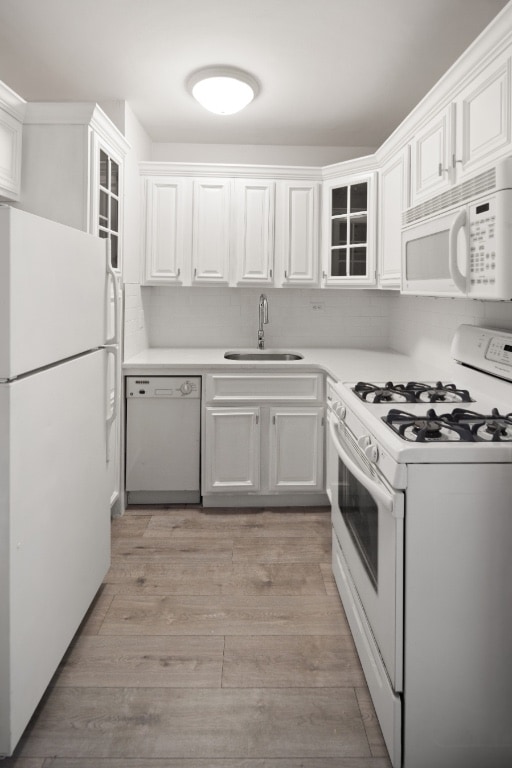 kitchen with white cabinetry, sink, light hardwood / wood-style floors, and white appliances