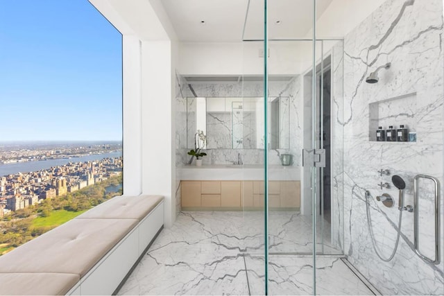 bathroom featuring a water view, marble finish floor, a marble finish shower, and vanity