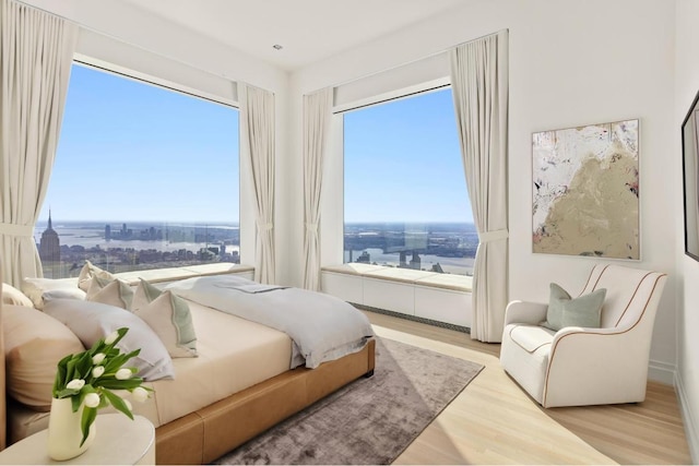 bedroom with light wood-style flooring and a city view