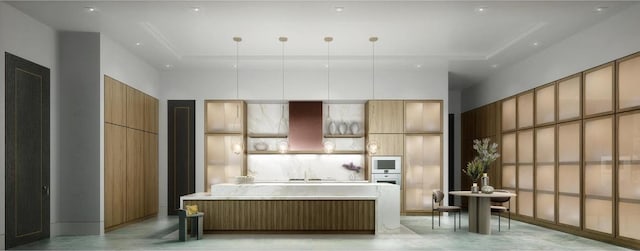 kitchen featuring a center island, a tray ceiling, light countertops, hanging light fixtures, and white microwave