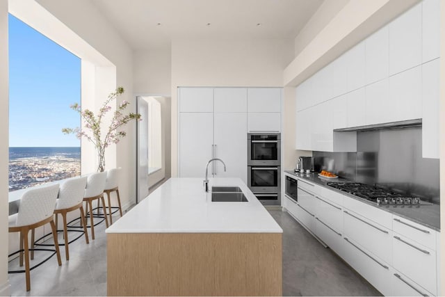 kitchen featuring white cabinetry, a center island with sink, appliances with stainless steel finishes, and a sink