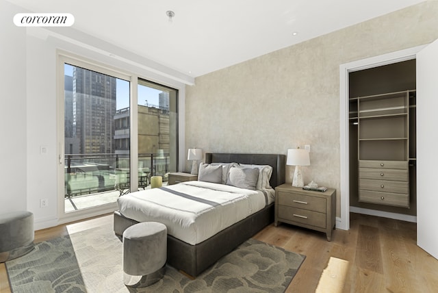 bedroom featuring light wood-type flooring, a spacious closet, a closet, and access to exterior