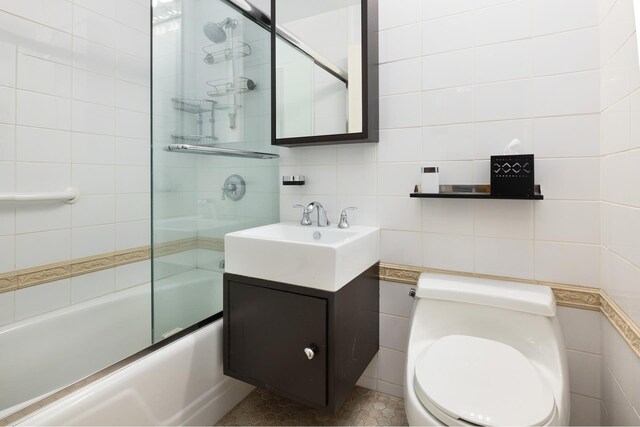 full bathroom with backsplash, toilet, vanity, enclosed tub / shower combo, and tile walls