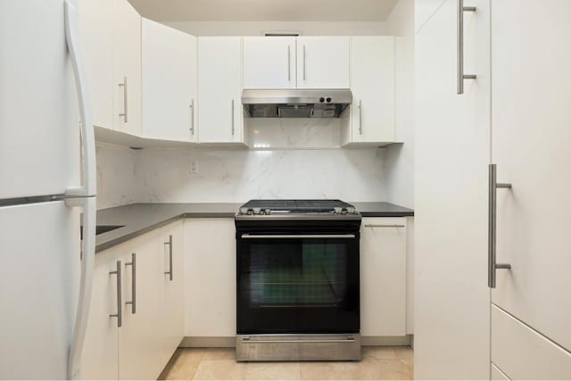 kitchen featuring white cabinetry, light tile patterned flooring, decorative backsplash, stainless steel range with gas cooktop, and white fridge