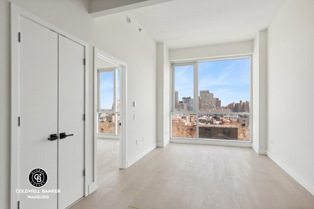 139 Bowery Unit 8C, New York City, NY 10002 - interior space with light wood-type flooring, a city view, and baseboards