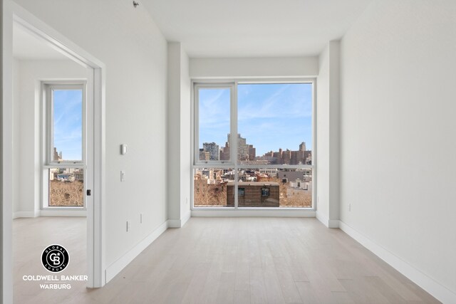 139 Bowery Unit 8C, New York City, NY 10002 - empty room featuring wood finished floors, a city view, and baseboards