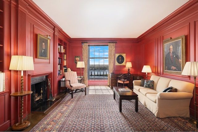 living area featuring built in features, ornamental molding, a fireplace, and a decorative wall