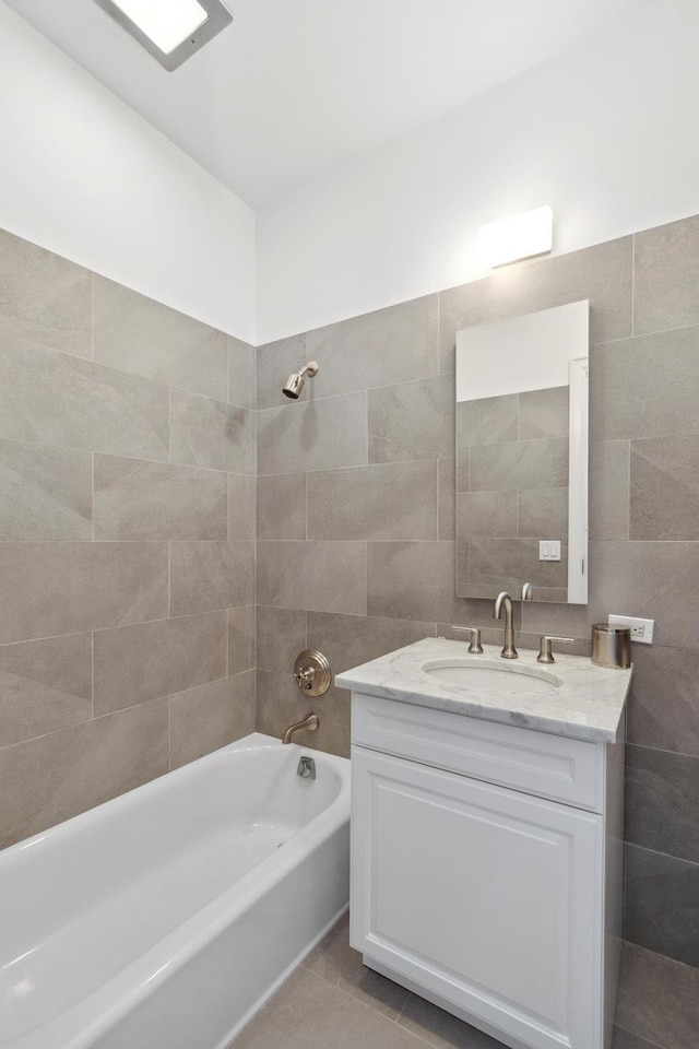 full bathroom featuring tile patterned flooring, shower / bathing tub combination, tile walls, and vanity